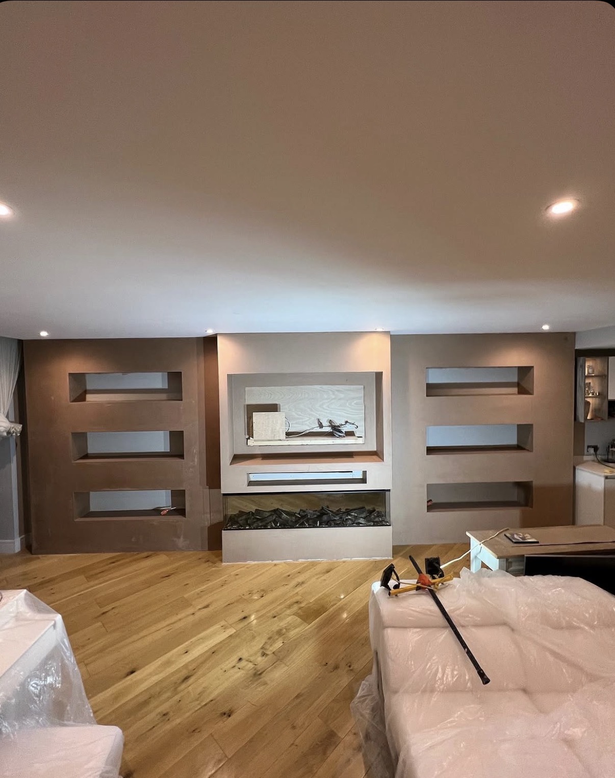 Bespoke plastered media wall with recessed shelving, ambient lighting and modern fireplace