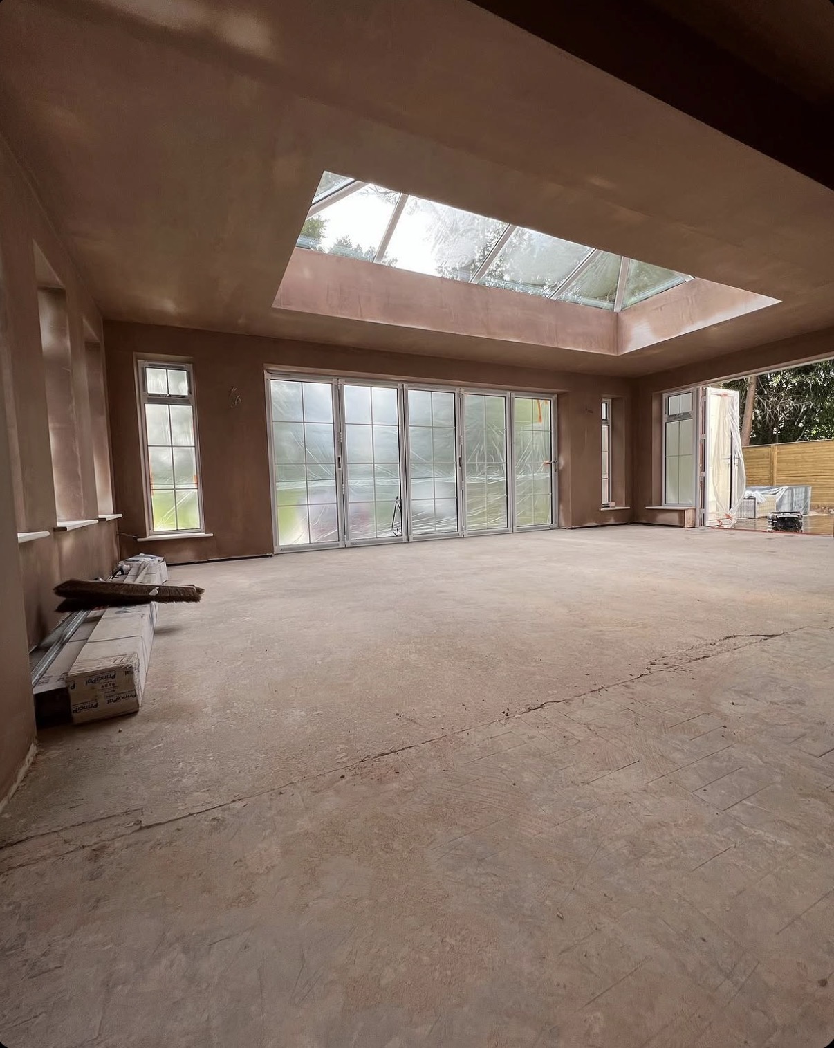 Freshly plastered extension interior with bifold doors and roof lantern skylight